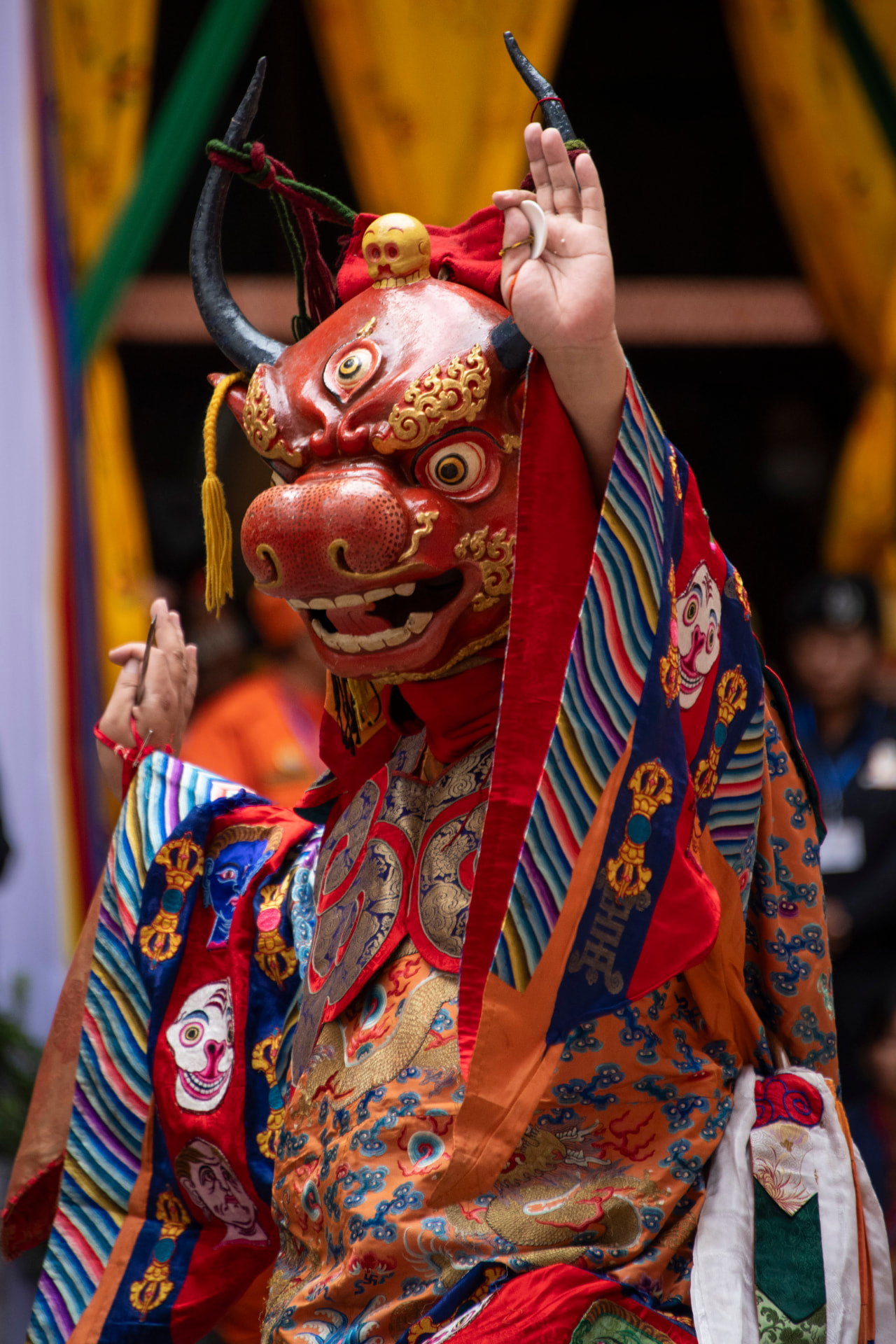 A performer in an ornate red mask and richly decorated costume during a Bhutanese cham dance
